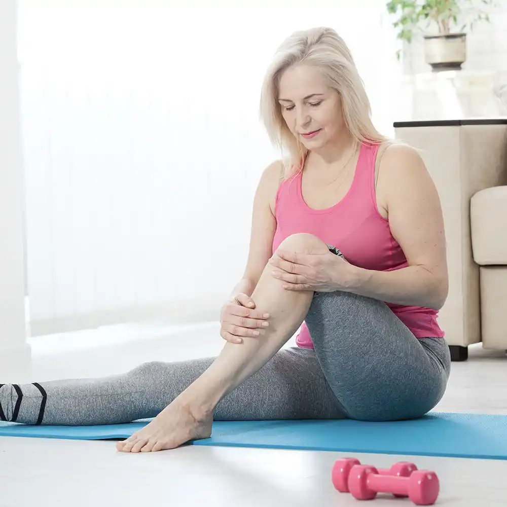 arthritis_img A woman stretching on a mat at home with dumbbells, promoting joint health after Osteoarthritis treatment in Miami, FL.